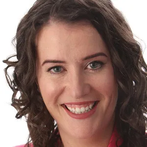 Meaghan Reitzel, with curly brown hair, smiles at the camera against a plain light background.