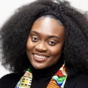 A smiling Bianca Okine, with natural curly hair, stands with her arms crossed, wearing a black top and a colourful patterned scarf.