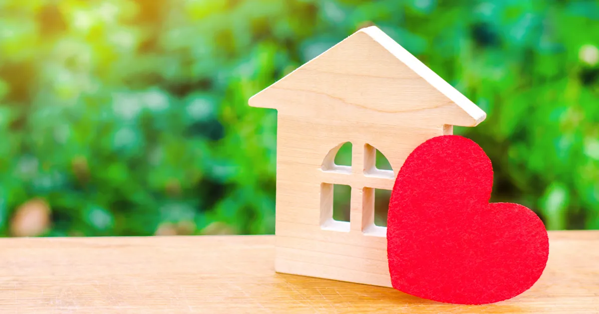 Wooden facade of a house. A red heart leans on the right corner of the house.
